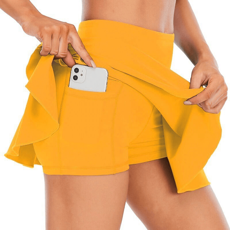 Energetic woman wearing yellow high waist tennis skirt-shorts with pocket, showcasing movement and comfort for active play.